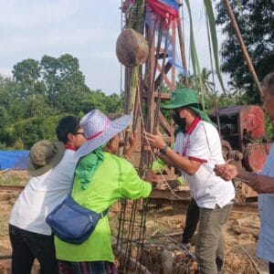 พิธีตั้งเสาเอกเสาโท โดยมีผู้คนร่วมมือกันผูกผ้าและตกแต่งเสา