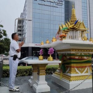 ชายกำลังไหว้ศาลพระภูมิหน้าอาคาร Isuzu